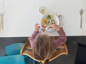 Ein Kind sitzt an einem Tisch und isst.