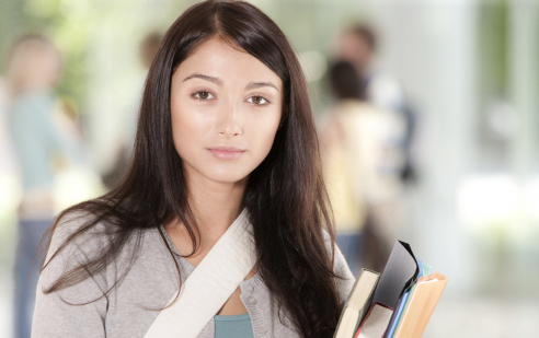 Eine junge Frau schaut direkt in die Kamera. Sie hält verschiedene Bücher im Arm. 